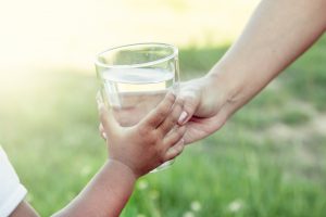 adult handing child a glass of water